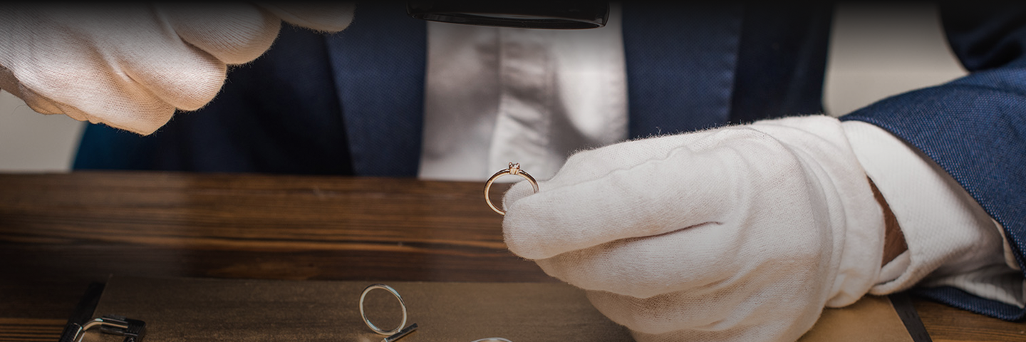 a Gold expert looks at gold jewellery with a magnifying glass
