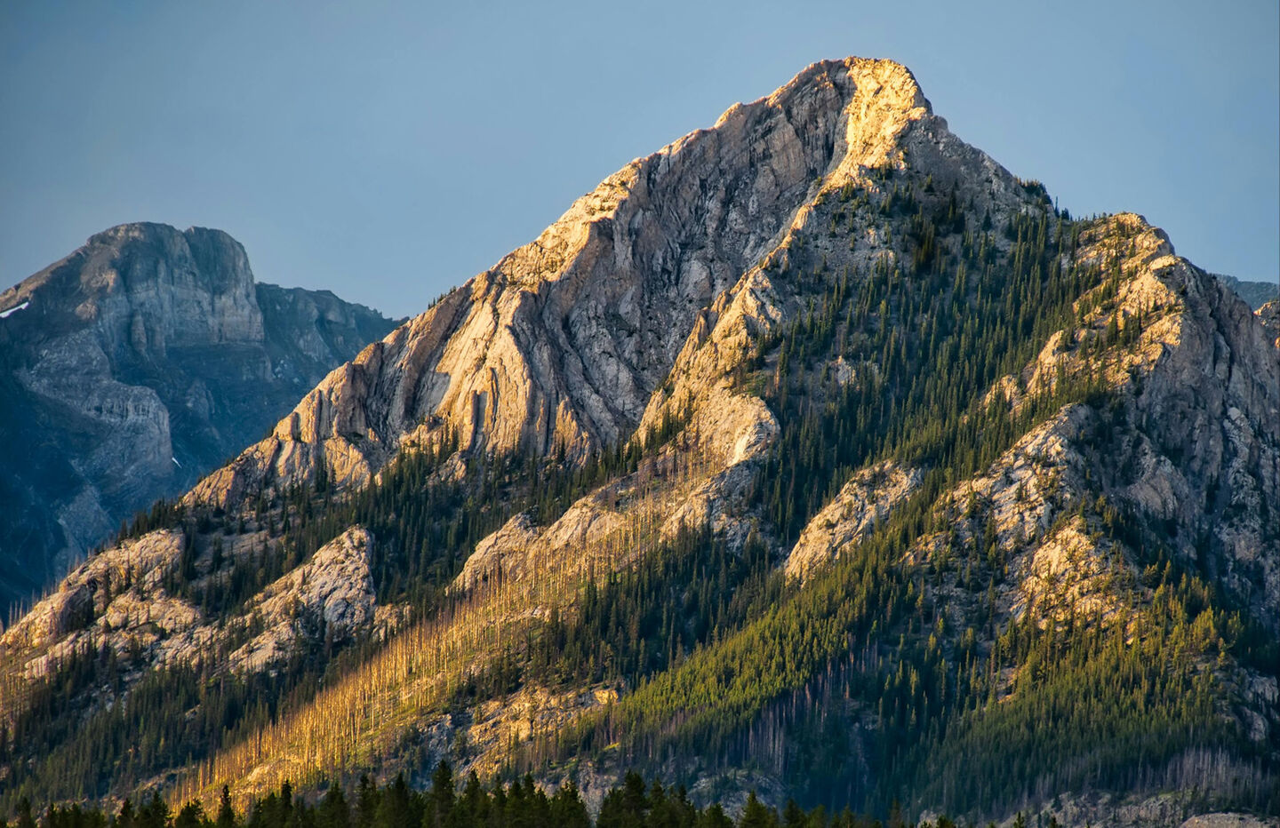 The sun shines on a towering Canadian mountain peak 