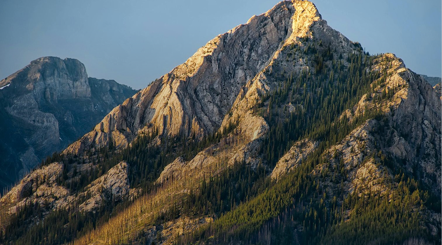 The sun shines on a towering Canadian mountain peak 