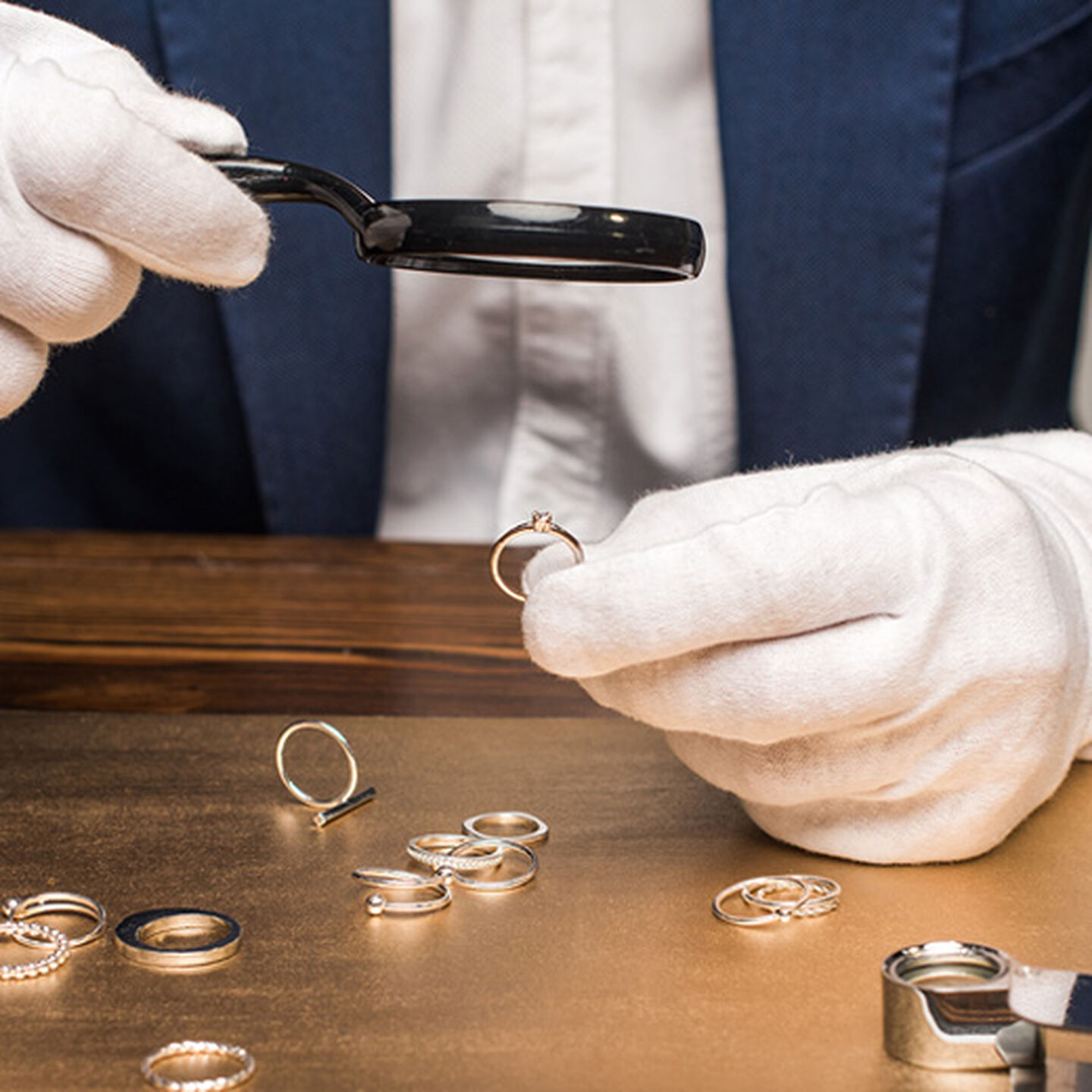 a jewellery expert inspects gold under a magnifying glass